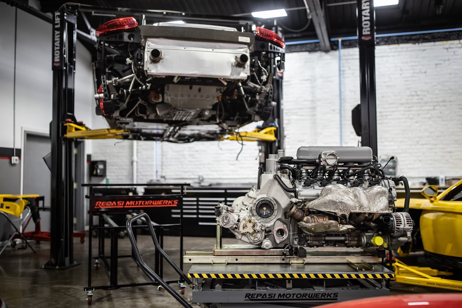 Porsche on a lift with its engine removed onto a cart below during engine-out major service at Repasi Motorwerks