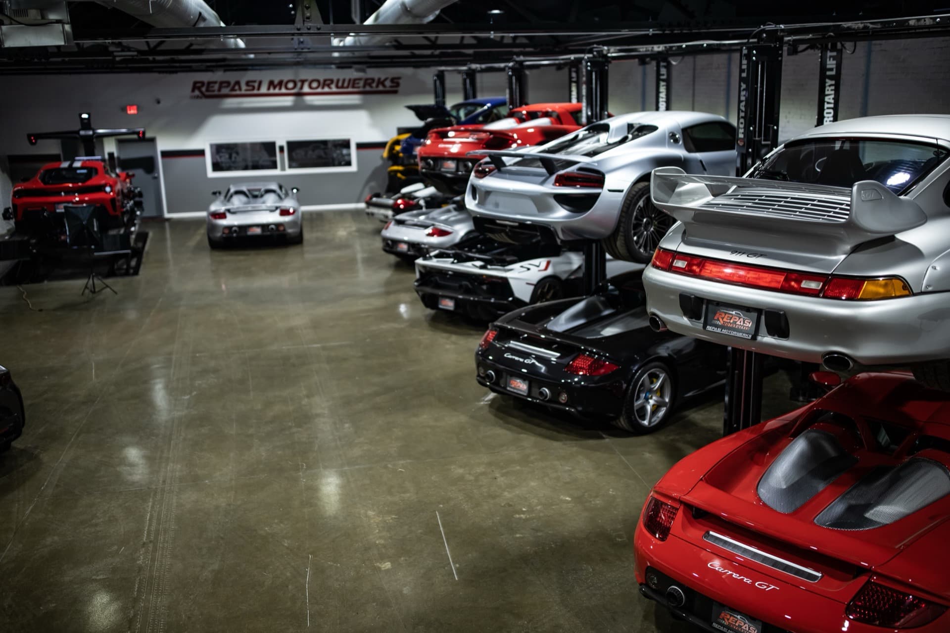 Wide overview of Repasi Motorwerks shop floor with multiple Carrera GTs and a LaFerrari on lifts